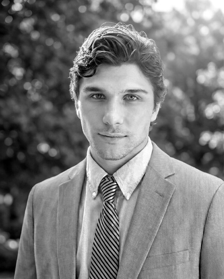 Portrait of a founder in a blazer and striped tie, among trees.