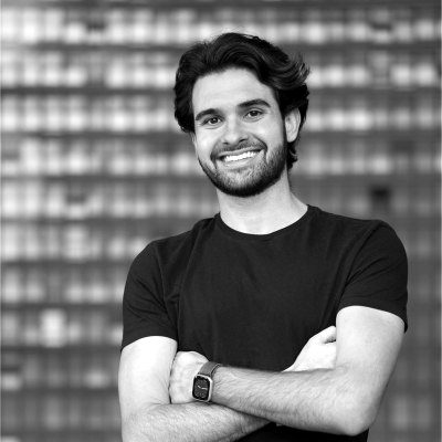 Smiling founder with arms crossed in front of an office building.