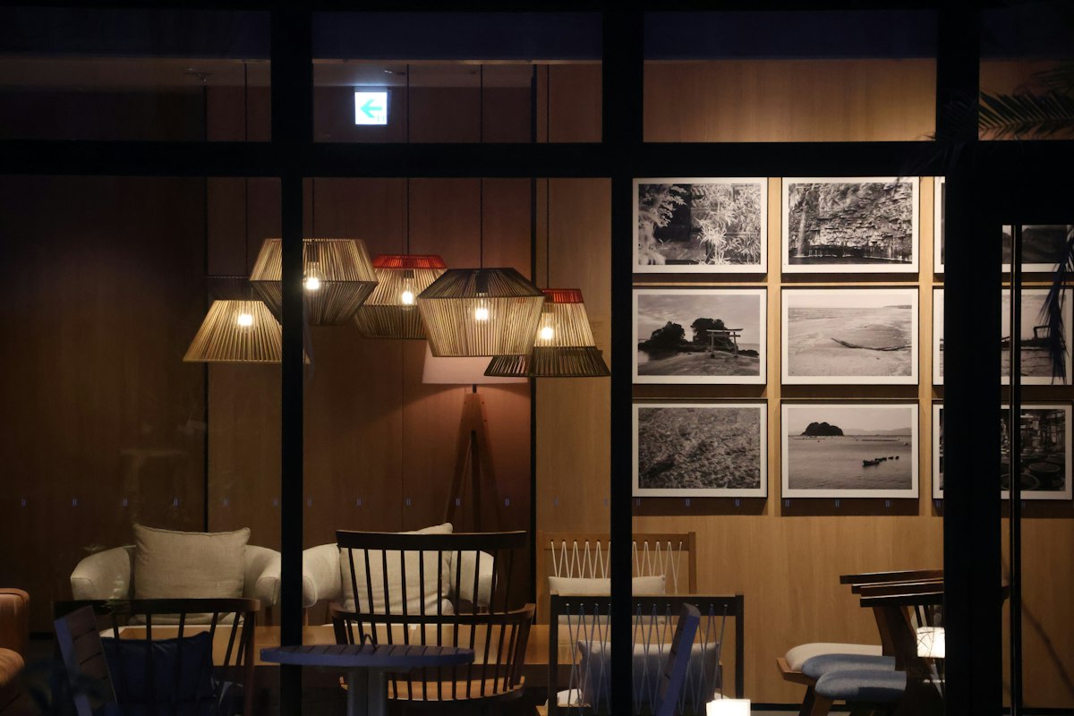 A warm evening interior with timber, softly glowing lamps and cushioned chairs.