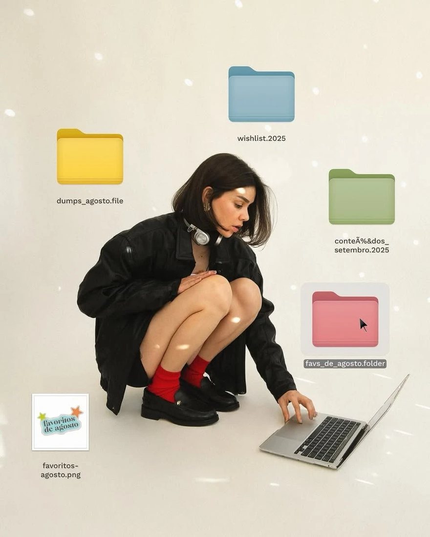 A person crouching beside a laptop on the floor, surrounded by floating colourful desktop folder icons.